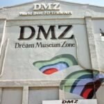 Front of the DMZ Dream Museum Zone building with a large 'DMZ' sign, 'Dream Museum Zone' subtitle, and a colorful abstract mural on the wall.