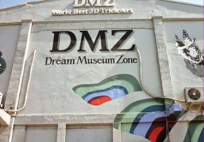 Front of the DMZ Dream Museum Zone building with a large 'DMZ' sign, 'Dream Museum Zone' subtitle, and a colorful abstract mural on the wall.