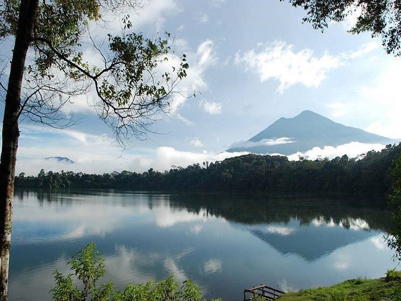 Calm lake reflecting the sky, clouds, and a distant forested mountain.