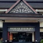 Front view of a museum entrance with a decorative triangular gable and a sign reading 'MUSEUM SIGINJEI' above the doors, flanked by planters.