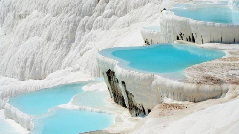 Turquoise terraced hot springs cascading over white travertine at Pamukkale, Turkey.