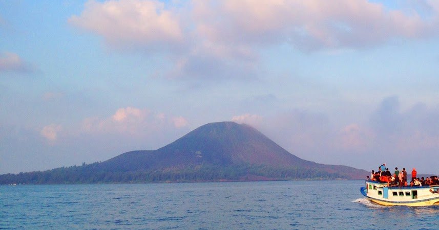 Calm sea with a hill-shaped volcanic island on the horizon and a crowded boat on the right side.