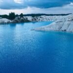 Turquoise lake with white limestone cliffs and an overcast sky in the distance