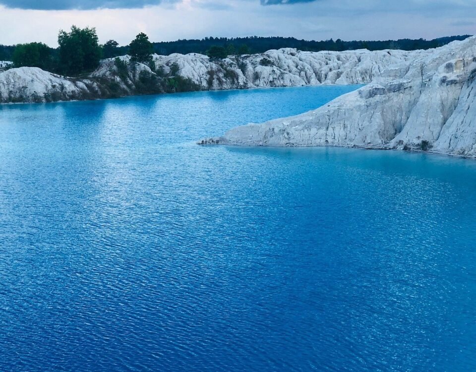 Turquoise lake with white limestone cliffs and an overcast sky in the distance