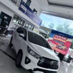 White Toyota SUV on a glossy showroom floor with banners and a large colorful 'Festival Tukar Tambah' poster in the background.
