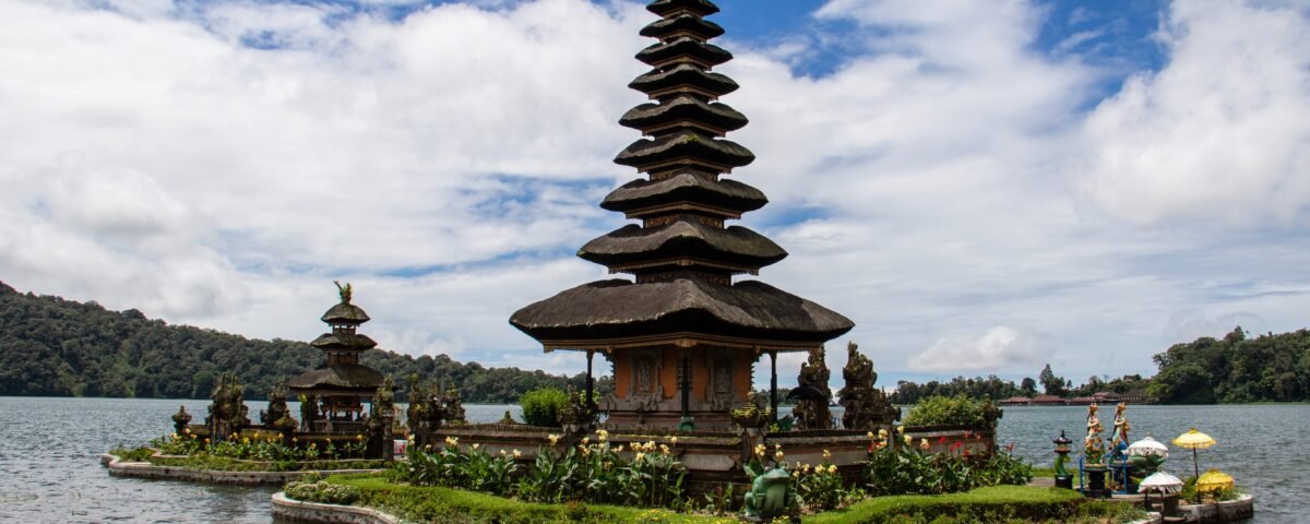 Multi-tiered stone pagoda on a small island in a lake, with sky and distant hills in the background.