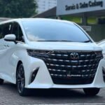 Front three-quarter view of a white Toyota Alphard minivan parked, showing the large black grille, chrome trim, and 'All New Alphard' badge.