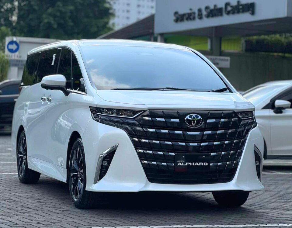 Front three-quarter view of a white Toyota Alphard minivan parked, showing the large black grille, chrome trim, and 'All New Alphard' badge.