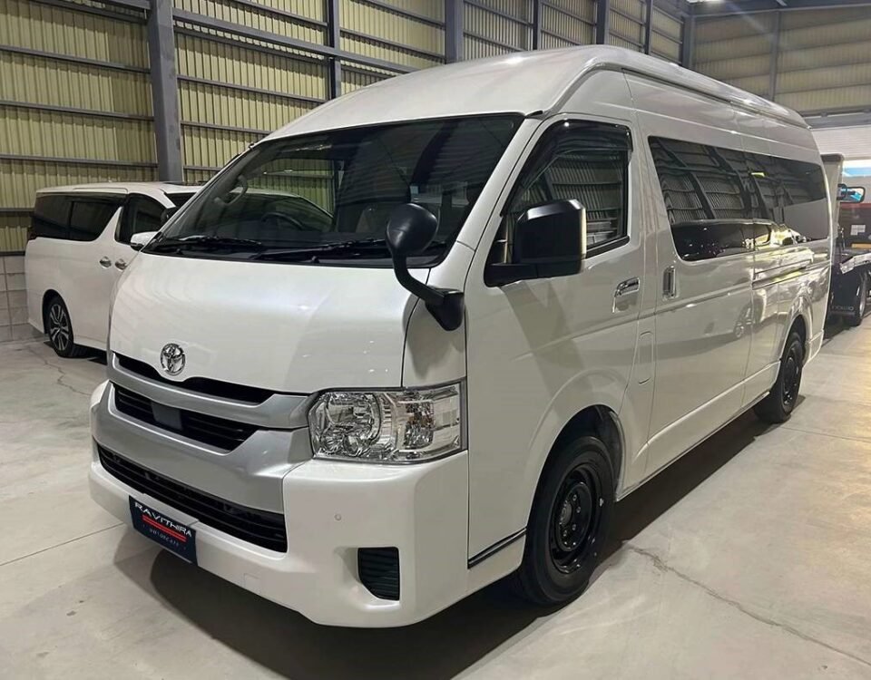 COMMUTER - Dyantransport White Toyota van in a showroom, front three-quarter view, clean and polished interior lighting reflecting off the body