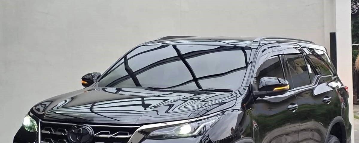 Black SUV parked on a paved driveway under a glass-covered carport.
