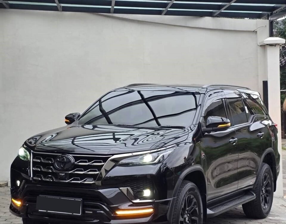 Black SUV parked on a paved driveway under a glass-covered carport.