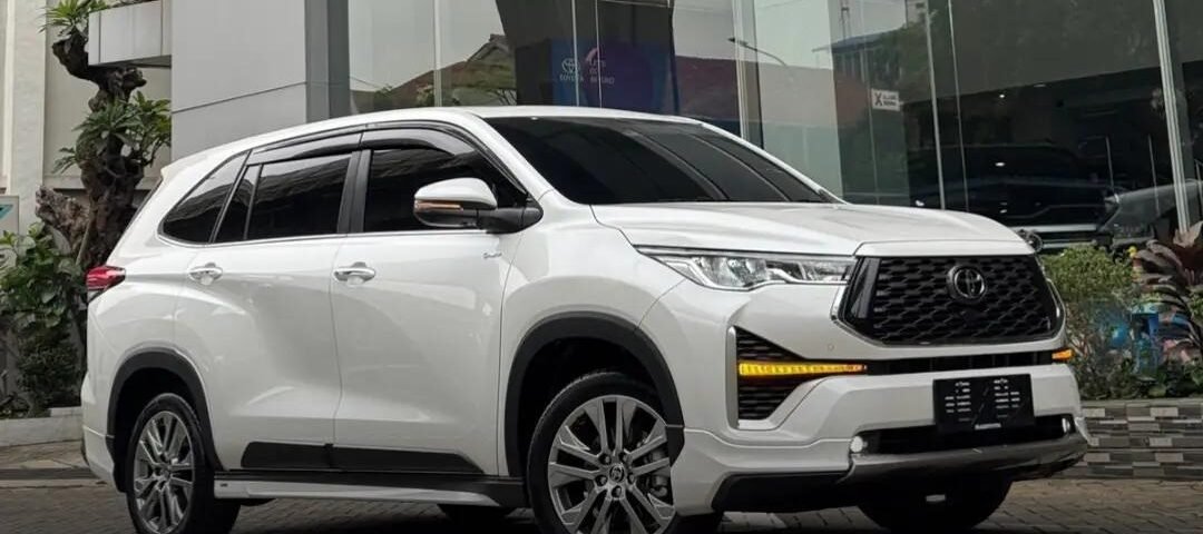 White Toyota SUV parked outside a modern glass-front dealership with the Toyota logo above it.