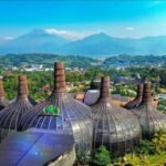 Cluster of bulb-shaped glass domes with wooden ribs in a tropical landscape, mountains in the background.
