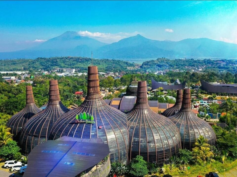 Cluster of bulb-shaped glass domes with wooden ribs in a tropical landscape, mountains in the background.