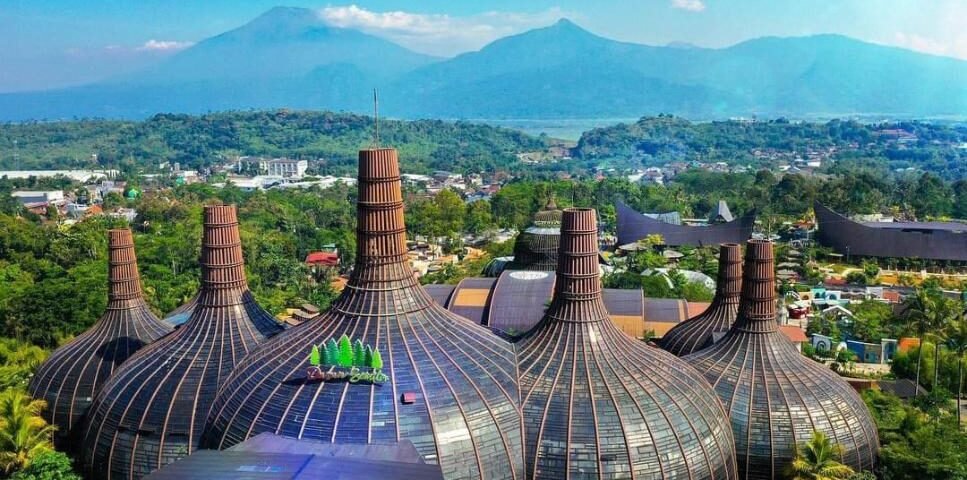 Cluster of bulb-shaped glass domes with wooden ribs in a tropical landscape, mountains in the background.