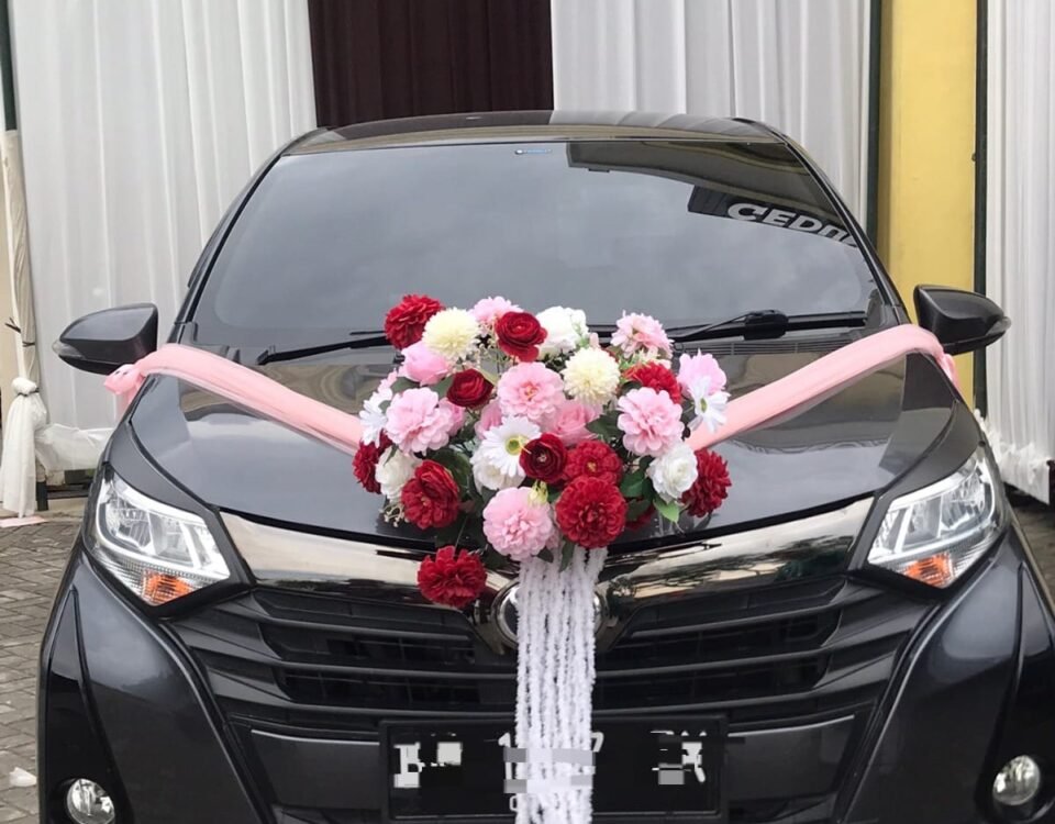 Black wedding car with pink ribbon and a large floral centerpiece (pink, white, red flowers) on the hood.