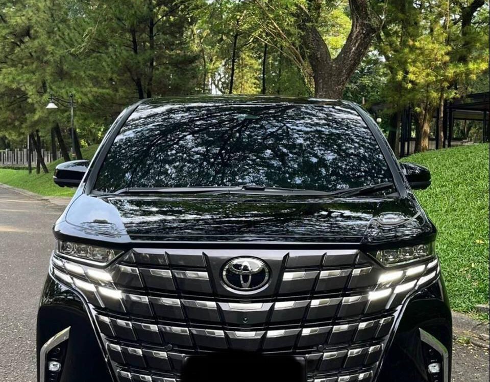 alphard canvas 1 - Dyantransport Front view of a black Toyota SUV with a large chrome grille parked on a tree-lined road.