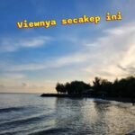 Beach at sunset with calm water and a tree-lined shore; bold yellow caption across the sky.