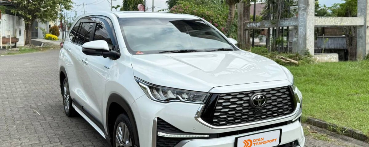Front three-quarter view of a white Toyota SUV parked on a street with the DyAn Transport logo in the corner.