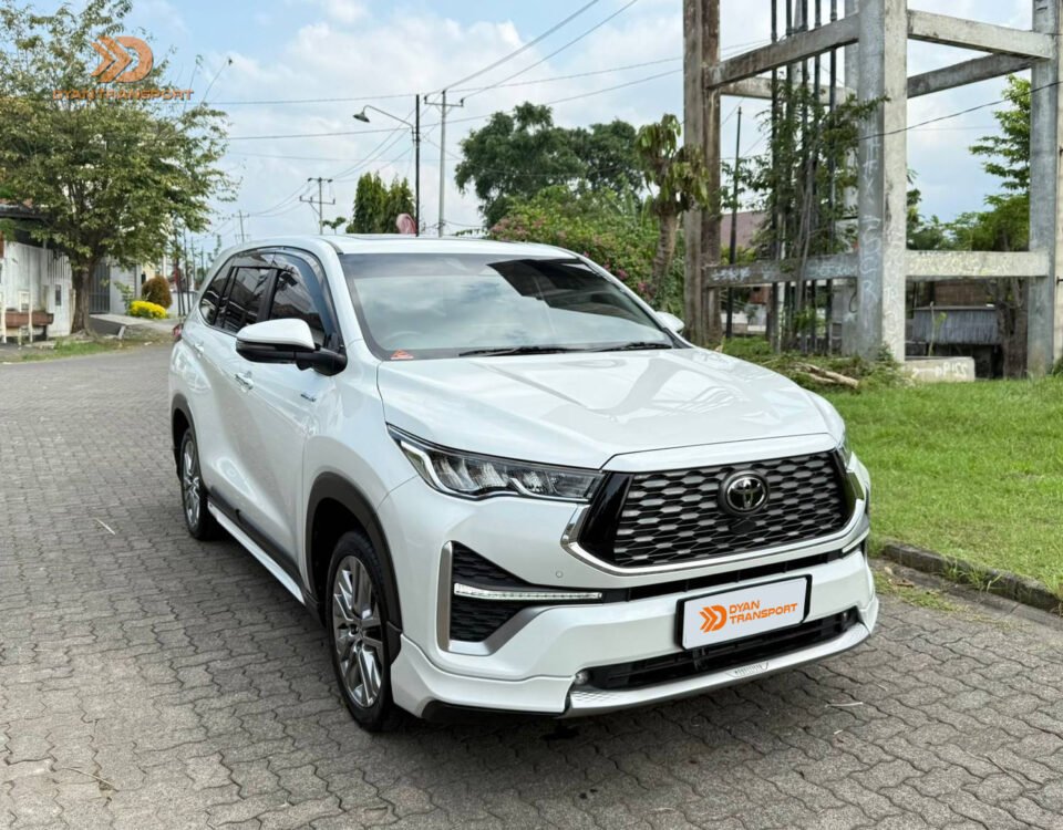 Front three-quarter view of a white Toyota SUV parked on a street with the DyAn Transport logo in the corner.