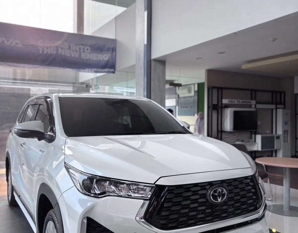 White Toyota SUV on display in a modern showroom, featuring a bold black grille and the orange DYAN TRANSPORT logo on the bumper.