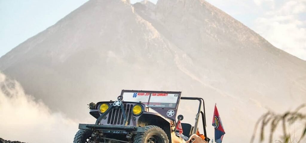 jeep 3 - Dyantransport Off-road jeep parked on rocky slope with a large mountain in the background; safety flagging gear visible on the vehicle edge.