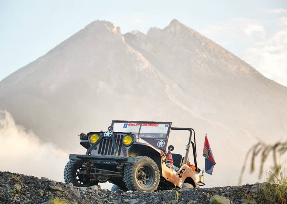 jeep 3 - Dyantransport Off-road jeep parked on rocky slope with a large mountain in the background; safety flagging gear visible on the vehicle edge.