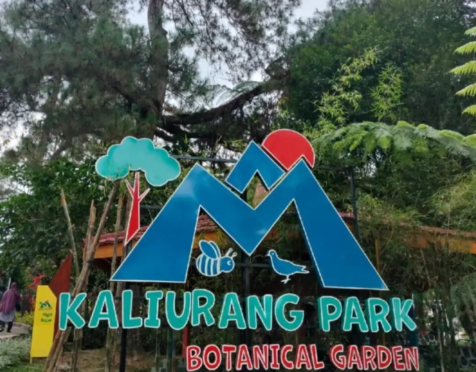 Sign for Kaliurang Park Botanical Garden with a blue mountain logo, red sun, tree, bee and bird illustrations