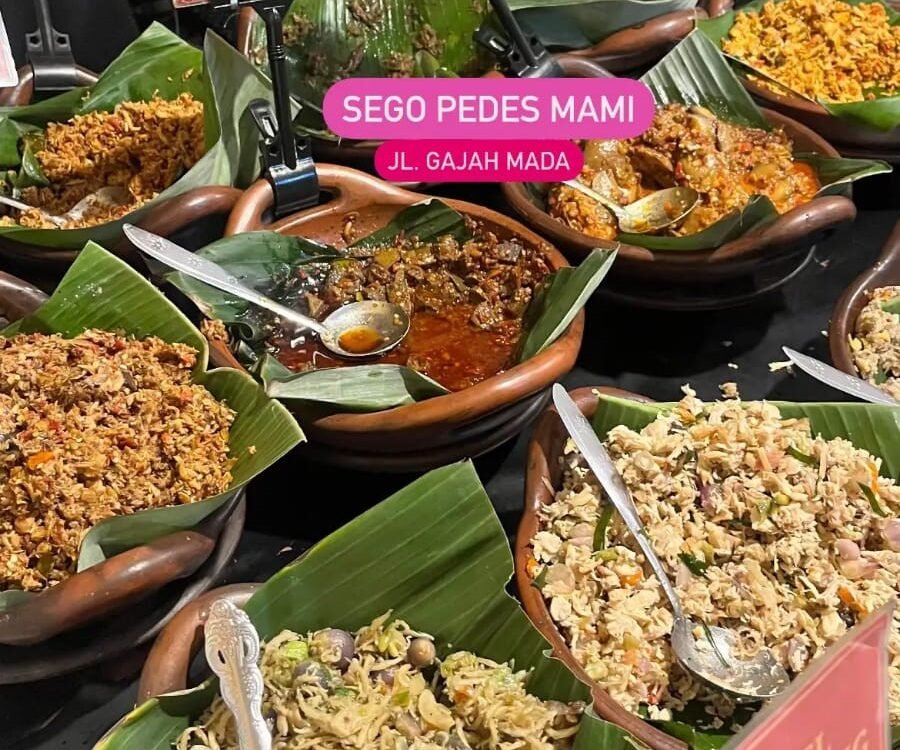 Assorted Indonesian dishes in clay bowls on banana leaves, with small labeled signs and spoons for serving, at a market stall