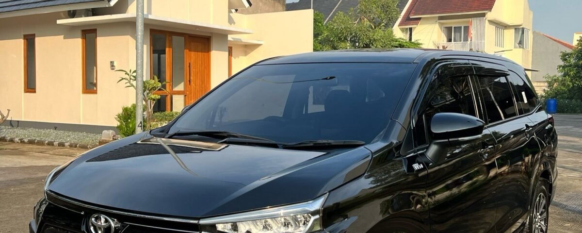 snaptik_7369070534291623174_2_v2 - Dyantransport Black Toyota SUV parked in a suburban driveway with beige houses and a tree in the background, under a blue sky.