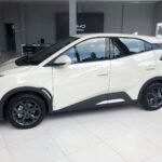 White crossover SUV on a showroom floor, shown in a side-front profile with black trim and dark alloy wheels.