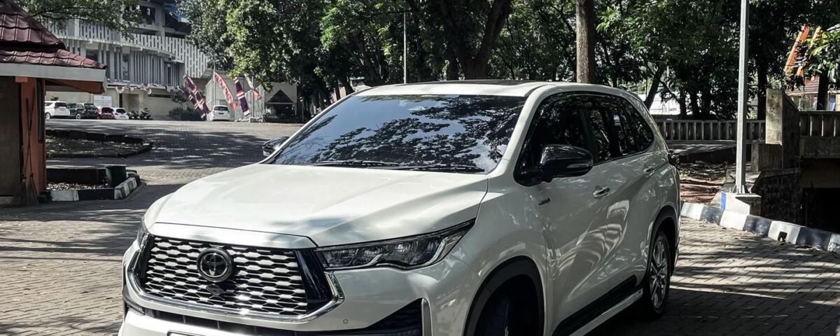 snaptik_7540270045507669265_1_v2 - Dyantransport White SUV parked on a brick-paved area with trees and a building in the background (front three-quarter view).