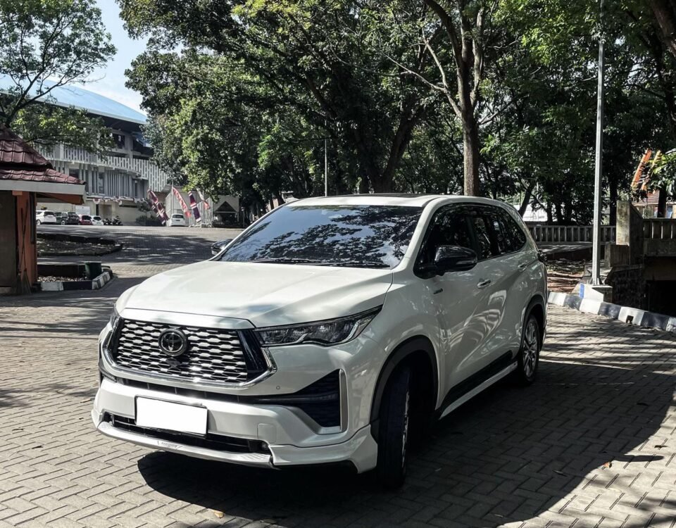 White SUV parked on a brick-paved area with trees and a building in the background (front three-quarter view).