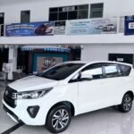 snaptik_7609535208643202312_7_v2 (2) - Dyantransport White Toyota SUV on a glossy showroom floor with promotional banners overhead in a dealership.