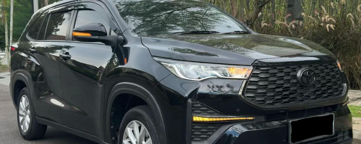 Black Toyota SUV parked on a street beside a tree and a modern gray building.