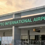 Facade of Adisutjipto International Airport with green lettering and a visible arrivals sign above the entrance.