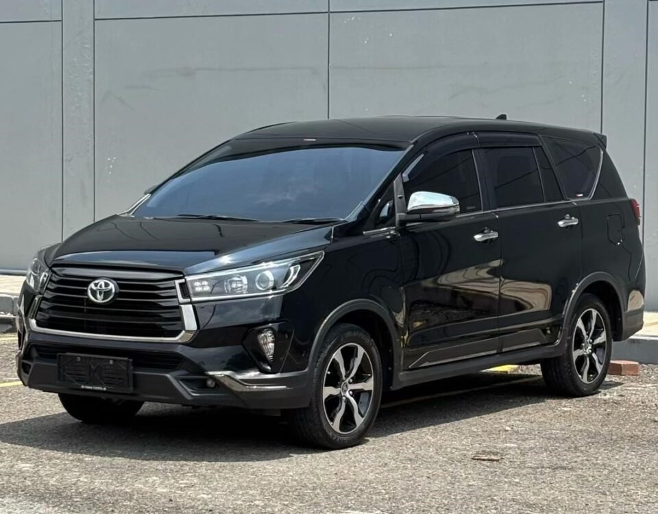 Black Toyota SUV (Highlander) in a parking lot near a grey panel wall, seen from a front-three-quarter angle with tinted windows.