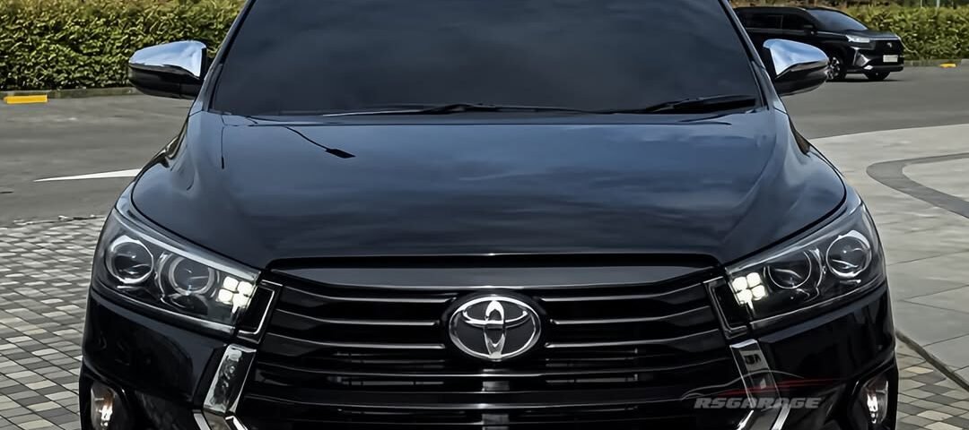 Front view of a black Toyota SUV parked on a tiled plaza, chrome grille and emblem centered on the grille.