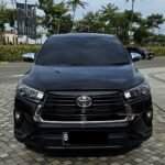 Front view of a black Toyota SUV parked on a tiled plaza, chrome grille and emblem centered on the grille.