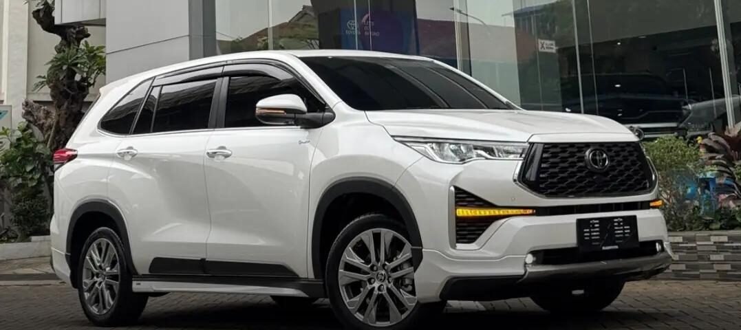 White Toyota SUV parked outside a glass-walled showroom, angled view showing front and side.