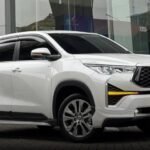 White Toyota SUV parked outside a glass-walled showroom, angled view showing front and side.