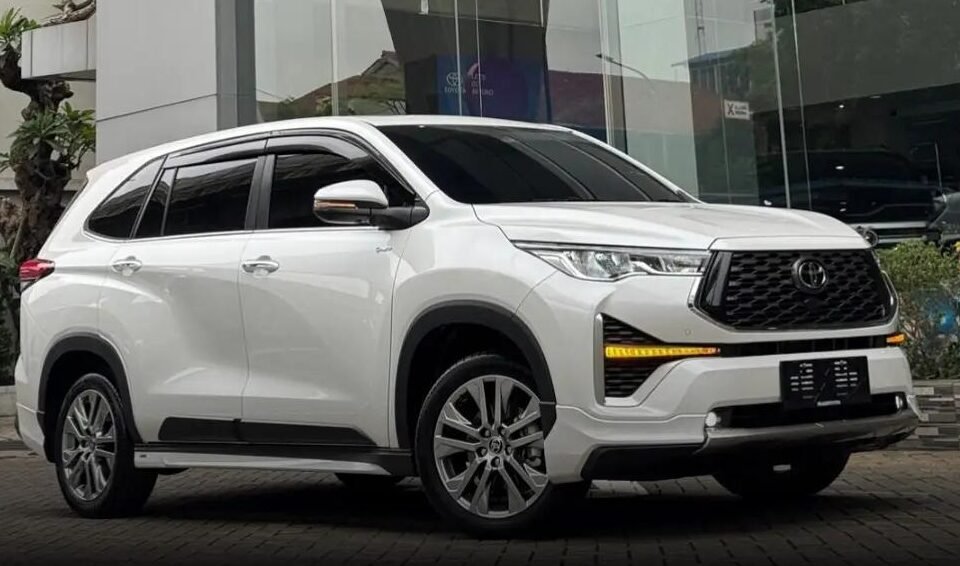 White Toyota SUV parked outside a glass-walled showroom, angled view showing front and side.