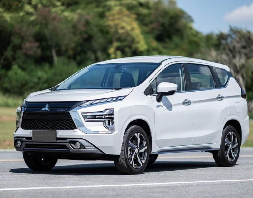 White Mitsubishi SUV shown in a three-quarter front view on a sunny roadway with trees in the background.