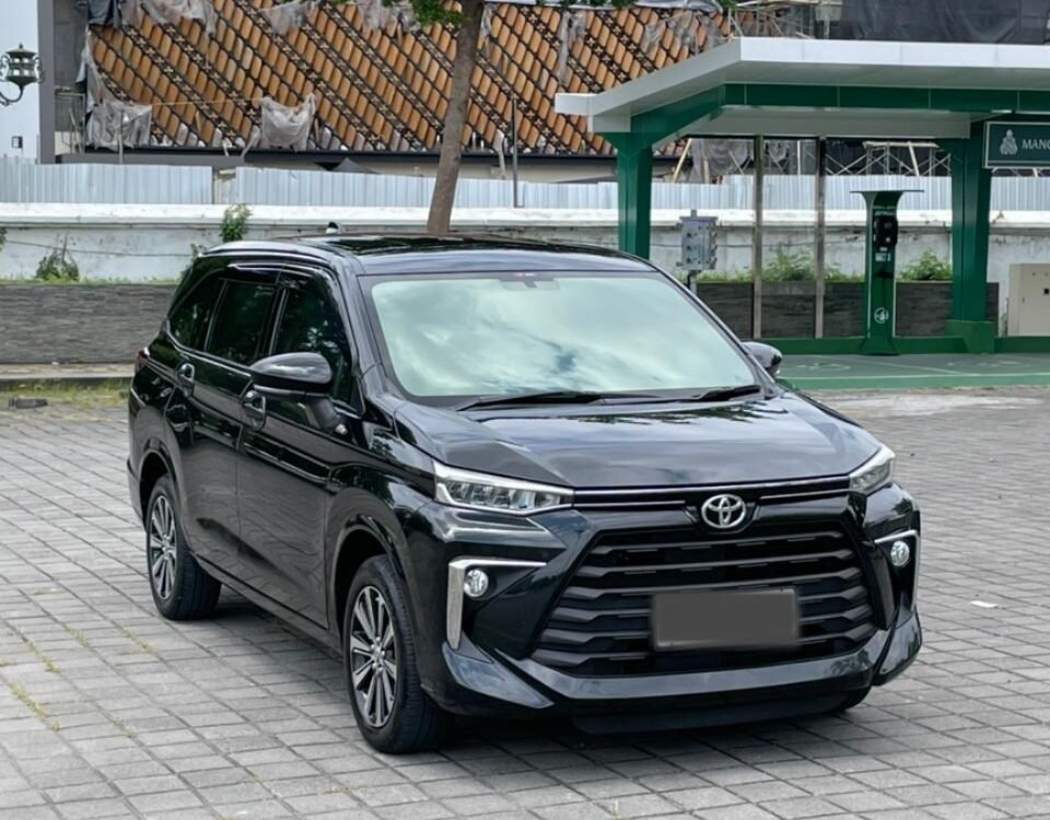 Front three-quarter view of a black Toyota SUV parked on a gray brick lot with a construction site and green canopy in the background.