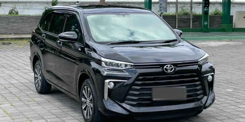 Front three-quarter view of a black Toyota SUV parked on a gray brick lot with a construction site and green canopy in the background.