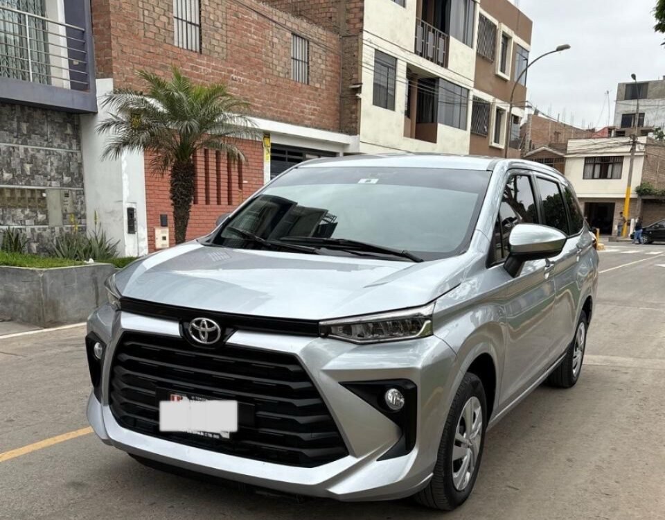 Silver Toyota SUV parked on a residential street with brick buildings, a palm tree, and a yellow curb line in the background.