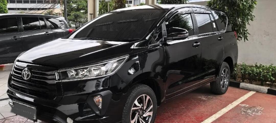 Black Toyota SUV parked in a covered parking area with wet red-tiled floor and white lines.