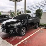 Black Toyota SUV parked in a covered parking area with wet red-tiled floor and white lines.