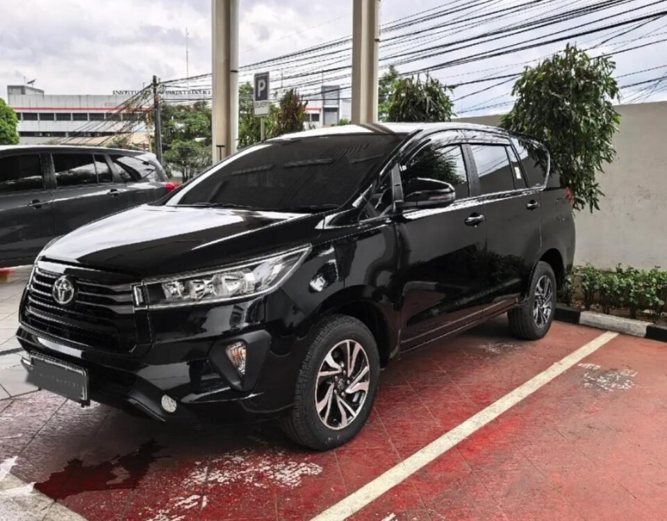 Black Toyota SUV parked in a covered parking area with wet red-tiled floor and white lines.