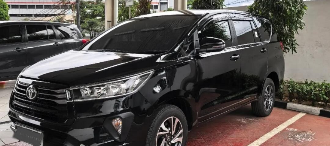 Black Toyota SUV parked in a covered parking area with wet red-tiled floor and white lines.